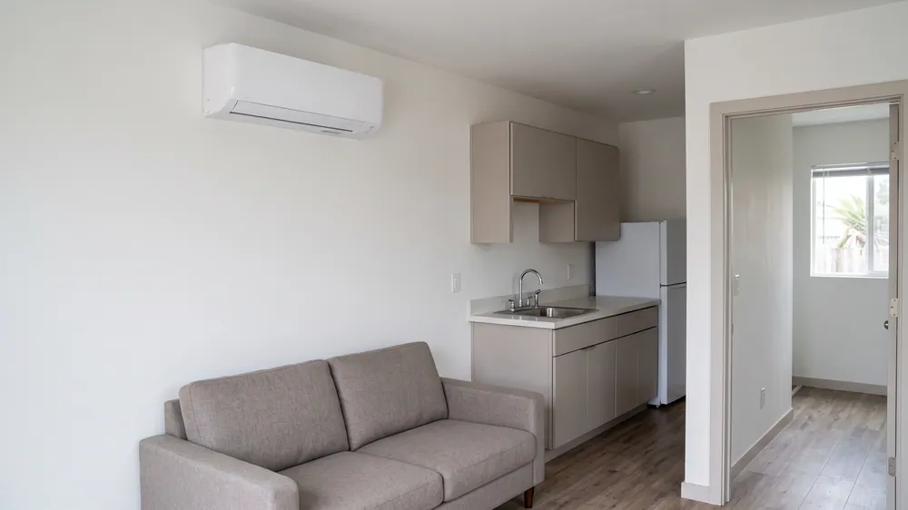 Wall-mounted mini-split in a compact ADU living area beside a kitchenette.