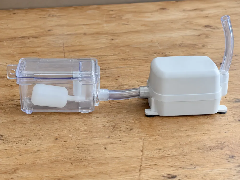 Condensate-pump components with a clear reservoir and connecting tube.