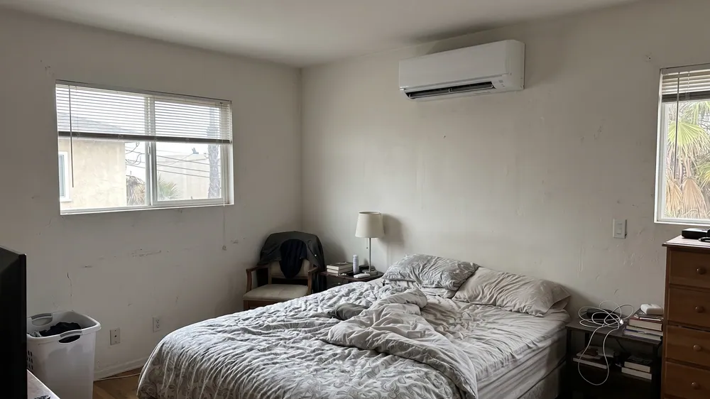 Wall-mounted mini-split above a modest bedroom.